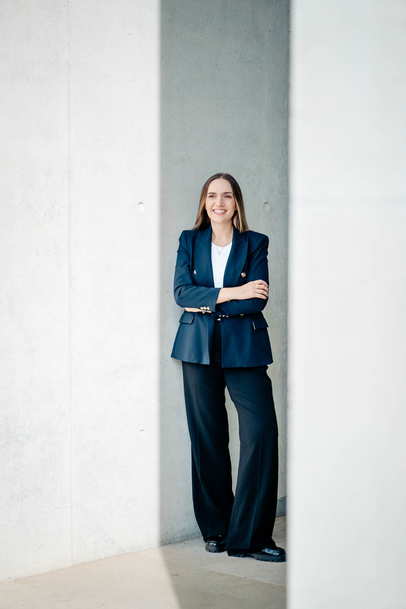 a woman in a suit leaning against a wall
